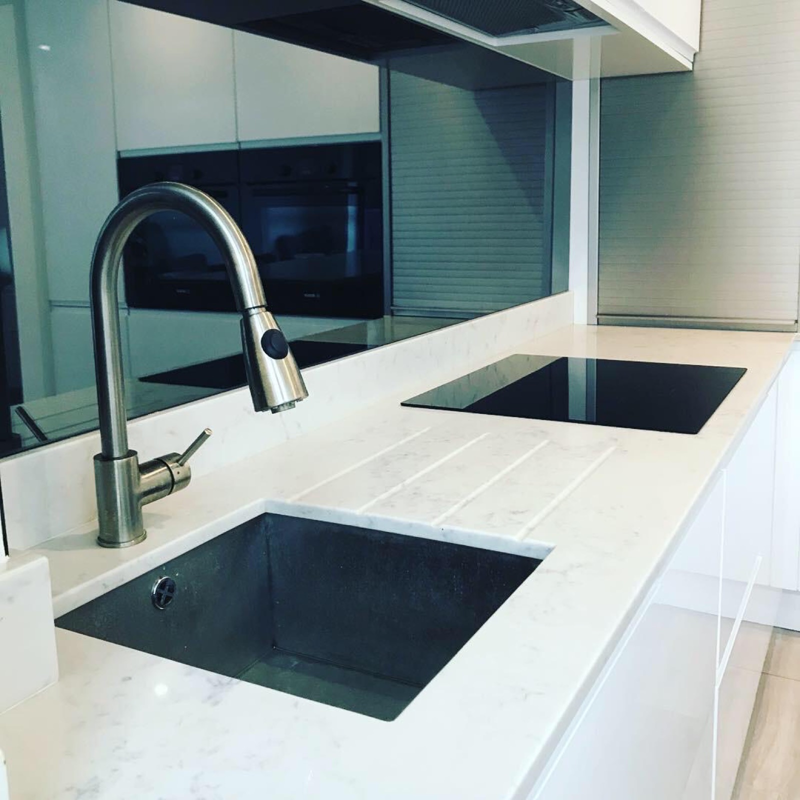 Close-up of a marble island worktop with a black undermount sink and hob