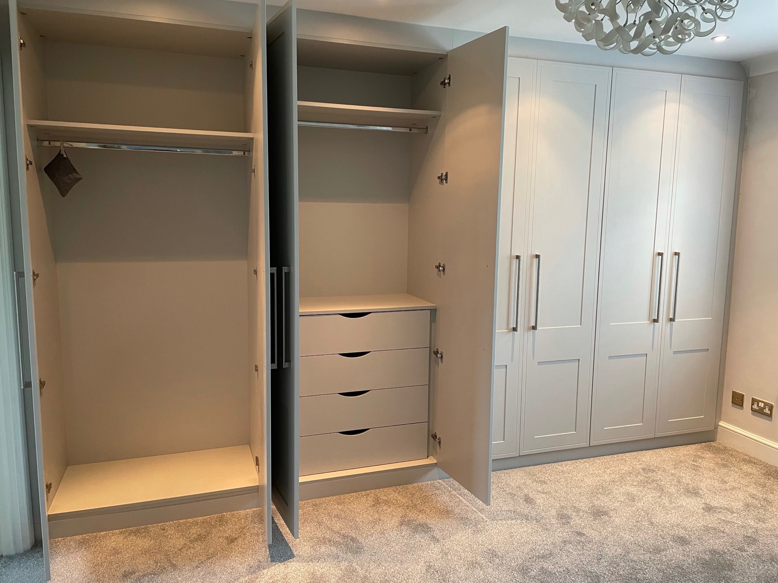 Light grey wardrobe with doors open showing hanging rails and fitted drawers